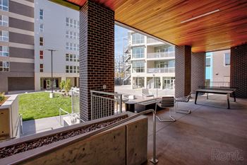 A modern outdoor seating area with a wooden ceiling and a view of a train track.